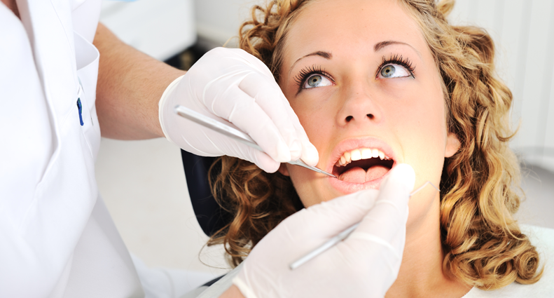 dentist performing oral cancer screening on woman for oral cancer early detection and prevention