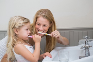 Pediatric Dental Health - Happy mother and daughter brushing their teeth