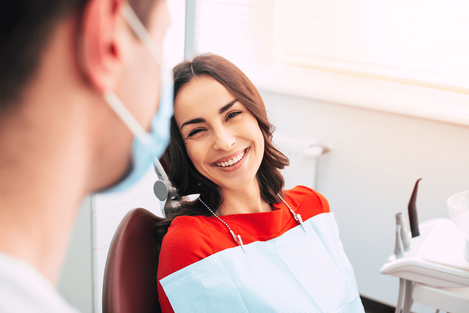 A woman smiling at the dentist after receiving her dental bridge