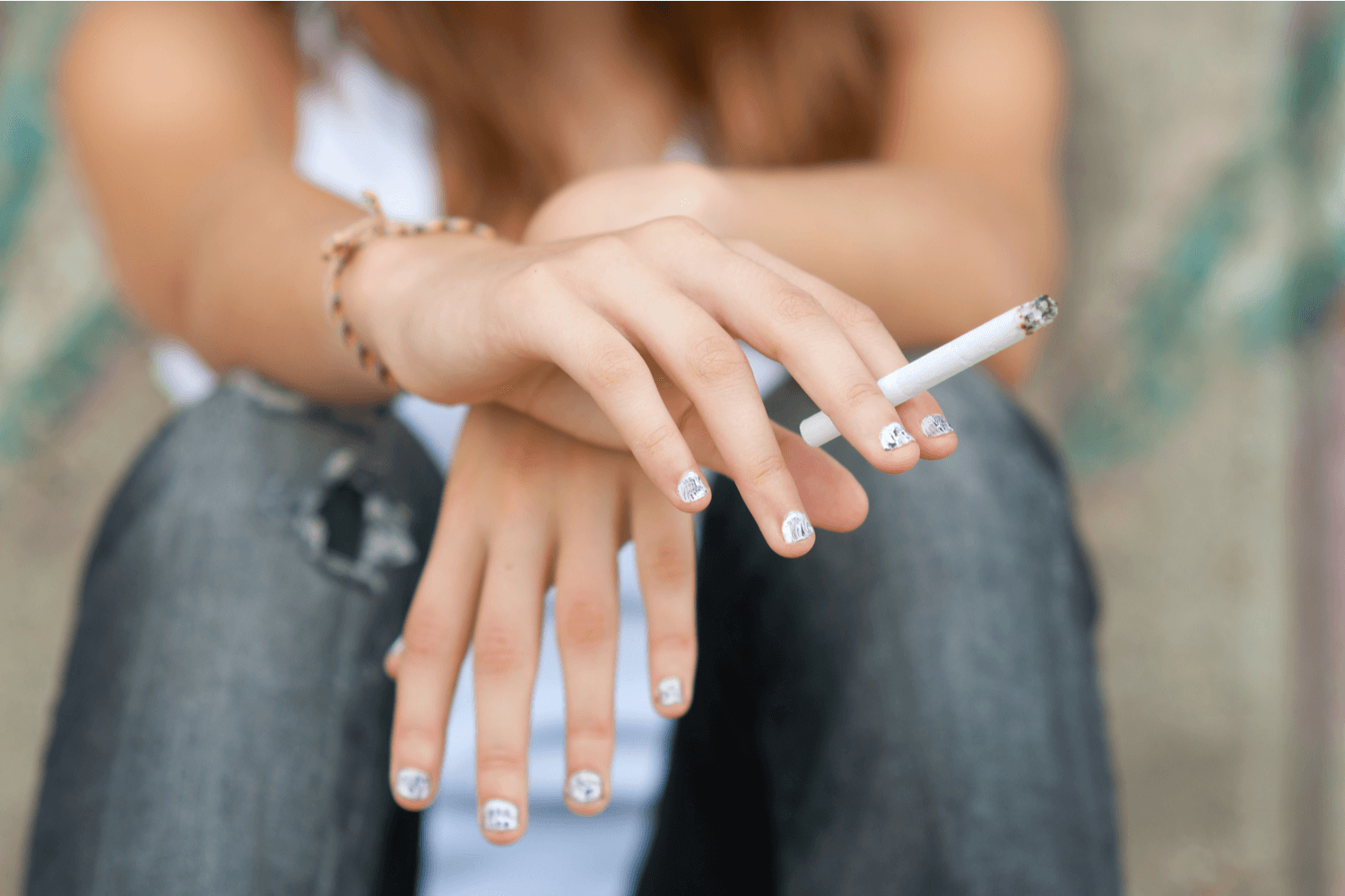 A teen girl holding a cigarette in her hands
