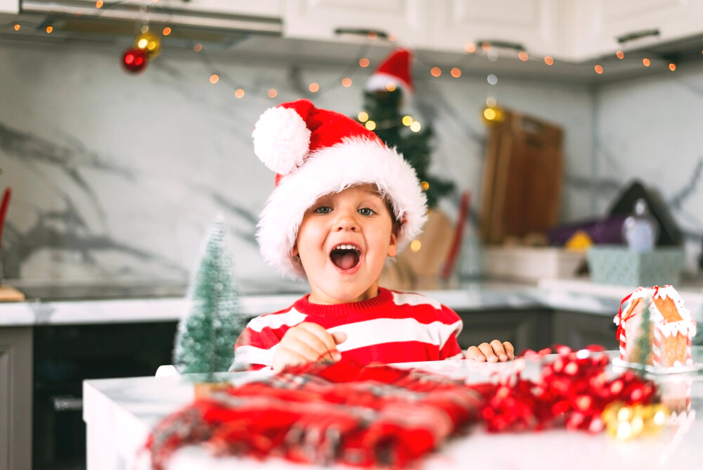 A cute excited little boy dressed in Santa pjs and is excited for Christmas
